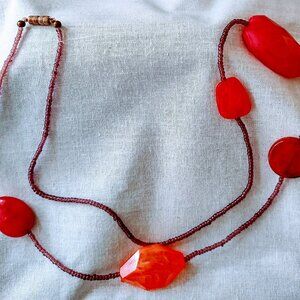 New long necklace made of large orange and seed beads.